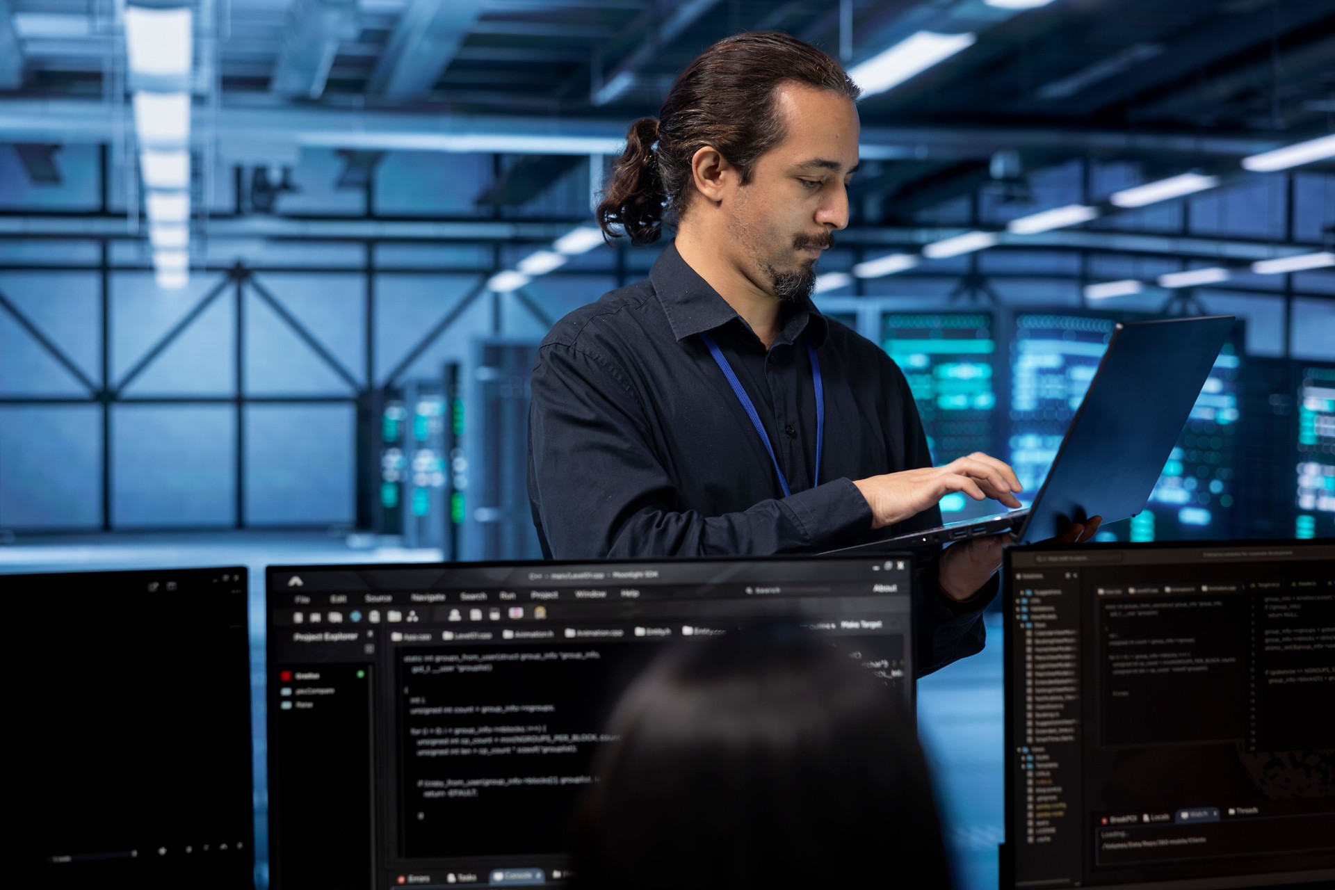 Engineer standing in data center, typing on laptop, doing yearly checkup